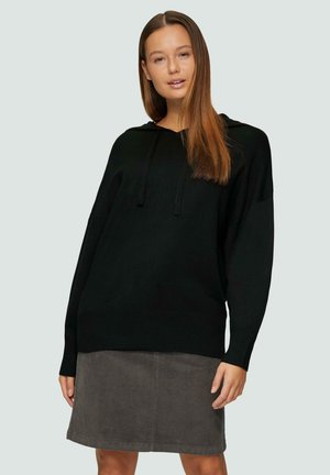 Zwarte hoodie van zachte stof, met een trekkoordkap, relaxed fit en lange mouwen. Gecombineerd met een grijze corduroy rok.