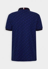 Polo bleu avec un motif géométrique. Col bleu marine et accent rayé à l'arrière du col. Manches courtes.