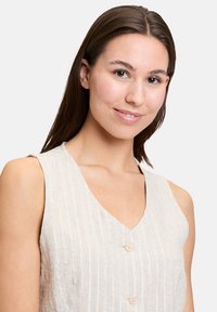 Haut sans manches rayé beige avec un décolleté en V, comportant deux boutons légers sur le devant, fabriqué en tissu texturé.