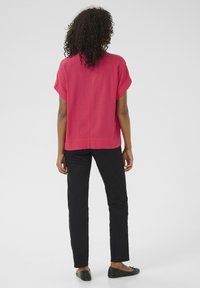 Haut rose à manches courtes avec une coupe décontractée, associé à un pantalon noir et des chaussures plates noires. Tissu lisse et lignes simples et épurées.