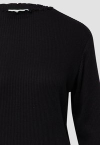 Maglione nero a coste con tessuto strutturato, vestibilità comoda e scollo smerlato. Le maniche lunghe esaltano il design semplice.