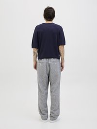 Marine oversized t-skjorte, løs passform. Gråstripete bukser med to baklommer, subtil tekstur. Hvite sneakers fullfører antrekket.