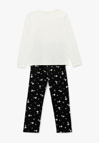 Hvid langærmet top parret med sorte pyjamasbukser, der har et gentaget mønster af tegneseriefigurer og stjernedesign i hvid og beige.