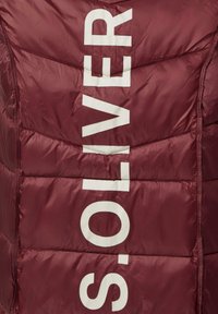 Bordeaux-gekleurde gewatteerde jas met een glanzende afwerking, voorzien van verticale witte tekst met de opdruk "S.OLIVER" en quiltsteekdetails.
