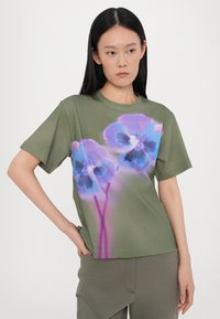 Olivgrünes T-Shirt aus weichem Material mit einem großen, lebendigen Blumenmuster in Blau und Lila, kurzen Ärmeln und Rundhalsausschnitt.