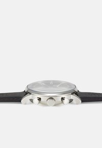 Montre en acier inoxydable argenté avec un cadran gris, un bracelet en cuir noir et trois boutons-poussoirs sur le côté. Verre lisse et design minimaliste.