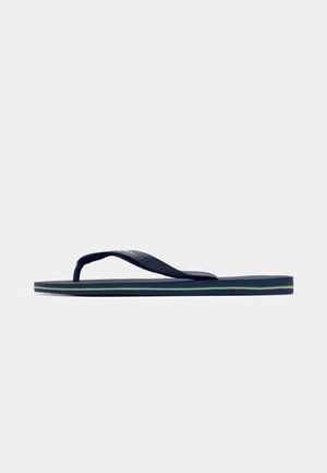 Tengerészi flip-flop szandál texturált gumipántokkal, formázott talpbéléssel és zöld csíkokkal a középtalpon. Lapos talp, laza dizájn.