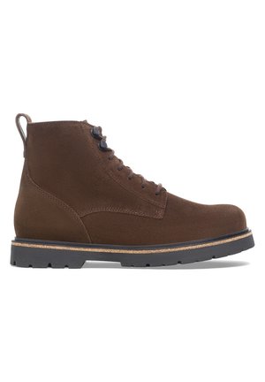 Brauner Wildleder-Schnürstiefel mit schwarzer Gummisohle mit Profil und Zuglasche an der Ferse, im Profil auf weißem Hintergrund dargestellt.