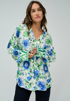 Camisa de botones floral en tonos verdes y azules, con fondo blanco, mangas largas con puños estampados y un escote en V.