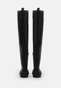 Botas negras hasta la rodilla con un acabado mate, que cuentan con una suela gruesa y cremalleras laterales. La palabra "BUFFALO" está grabada en la parte trasera.