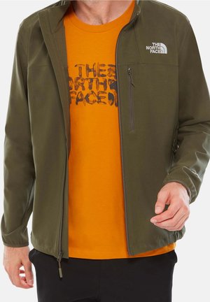 Homme portant une veste zippée vert olive avec le logo "The North Face" par-dessus un T-shirt orange avec le texte "The North Face" déformé.