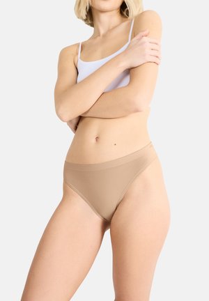 Beige seamless thong underwear with a wide waistband, made from smooth fabric, designed for comfort and minimal visibility under clothing.