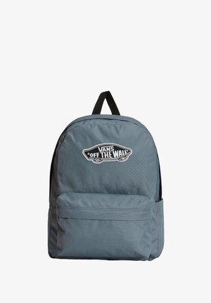Mochila de tela gris con una textura suave, que cuenta con un bolsillo frontal y un parche negro con el logo que dice "VANS 'OFF THE WALL'".