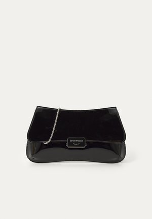 Bolso de manija de charol negro con forma estructurada, correa de cadena y cierre tipo solapa que presenta un acento metálico con detalle del logotipo.