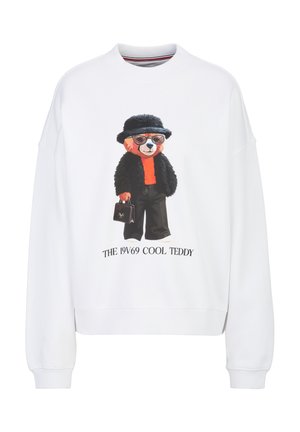 Witte trui met een teddybeer die een zonnebril, een zwarte hoed en jas draagt, een rood overhemd, en een kleine handtas vasthoudt met tekst eronder.