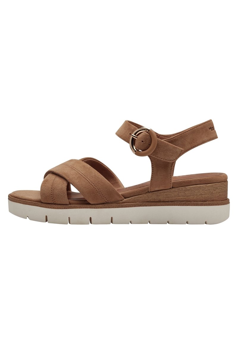 Tan suede sandal with crossover straps, adjustable ankle strap featuring a circular accent, and a chunky white platform sole.