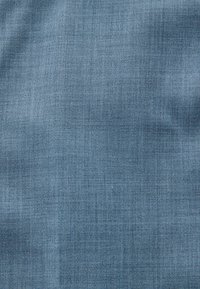 Tissu bleu texturé avec un motif finement tissé et des variations subtiles de nuances sur toute la surface.