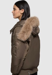 Brown puffer jacket with a fur-lined hood, featuring a glossy finish, side pockets, and a relaxed fit. Soft texture and insulated design.