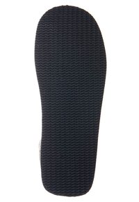 Gummisula på en sandal med texturerat, vågigt greppmönster i svart, visad från botten mot en vit bakgrund.