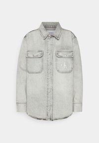 Světle šedá džínová košile s dlouhými rukávy, dvěma náprsními kapsami, knoflíkovou légou a decentním logem na levé kapse. Strukturovaná tkanina.