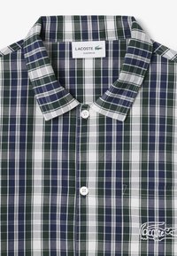 Camicia a maniche corte a quadri verde e blu navy, in cotone, con colletto a punte, chiusura con bottoni e logo ricamato sul lato sinistro del petto.