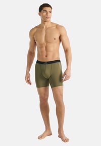 Miesten oliivinvihreät bokserialushousut, joissa on musta joustava vyötärönauha. Ne ovat sileärakenteiset ja istuvat, tarjoten täydellisen peiton.