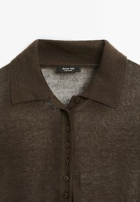 Braun gestricktes Polohemd mit Kragen, ausgestattet mit sieben dunklen Knöpfen und einem leicht strukturierten Stoff. Etikett im Kragen sichtbar.