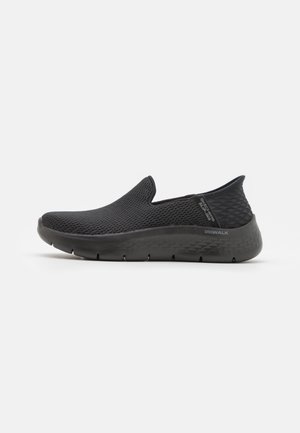 Scarpa sportiva nera slip-on con tomaia in mesh testurizzato, suola imbottita e dettagli a motivo diamante sul tallone.