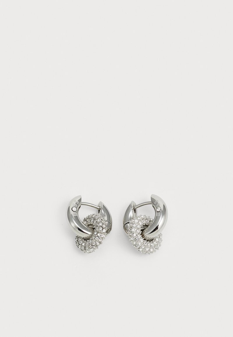 Pendientes de plata con un diseño retorcido que presenta elementos circulares y cristales transparentes engastados para mayor brillo.