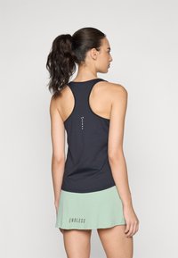 Mustmust mustriba tank top, mille kõverdatud sobivuse ja tekstureeritud kangaga. Tagaküljel on väikesed valged täpid ja sobib kokku piparmündirohelise seelikuga.