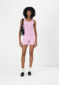Rosa stripete topp med blonder, kombinert med matchende rosa stripete shorts. En svart veske, hvite sokker og svarte sko fullfører antrekket.