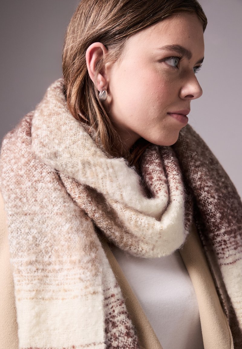 Wollen sjaal met een verloop van crèmekleur, beige en bruine tinten; zachte textuur met een mix van patronen; casual om de nek gewikkeld.