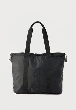 Crna torba za nošenje od najlona s dvjema dugim tkanim ručkama i gornjom stranom zatvorenoj patentnim zatvaračem te podesivim bočnim užadima.