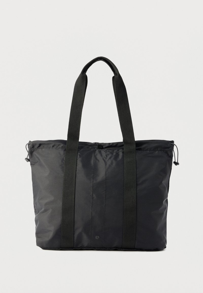 Μαύρη τσάντα χειρός από νάιλον με δύο μακριές υφασμάτινες λαβές και φερμουάρ στην κορυφή με ρυθμιζόμενα κορδόνια στα πλαϊνά.