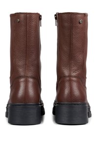 Brune lær ankle boots med en teksturert overflate, vertikale glidelåser og såle av svart gummi. Har minimalt med hardware aksenter.