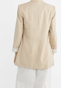 Beige linnen blazer met een aansluitende pasvorm, voorzien van lange mouwen en gestreepte manchetten, een gladde textuur en een enkele achteropening.