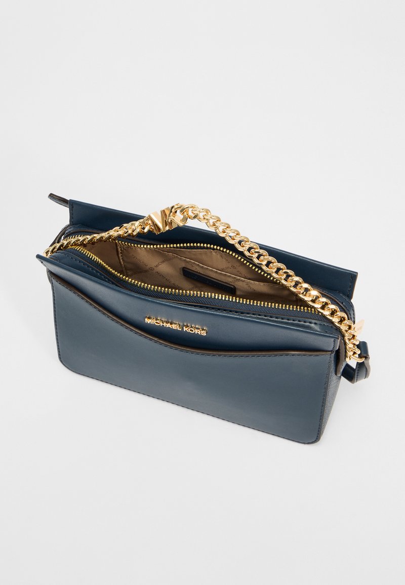 Navy leren handtas met een gouden kettingriem, rits-sluiting en gevoerde binnenkant, met een slank ontwerp en subtiele logo-afwerking.