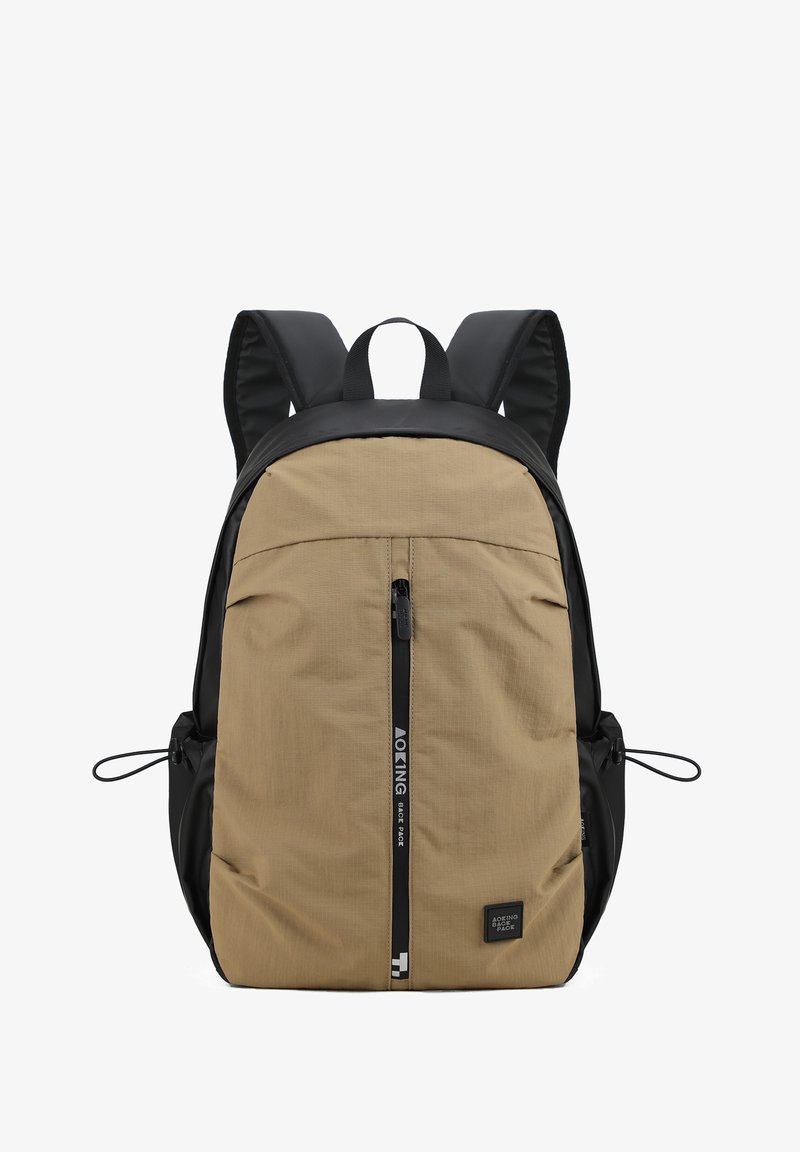 Sac à dos avec panneau avant beige et côtés noirs, doté d'une fermeture éclair frontale verticale, de deux poches latérales, de bretelles rembourrées et d'une poignée de transport supérieure.