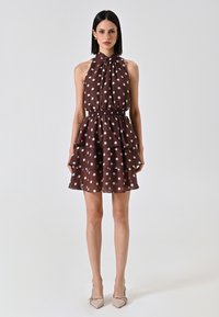 Braun gepunktetes Kleid mit Halterneck, Rüschentierchen und elastischem Bund. Hergestellt aus leichtem Stoff. Verfügt über weiße Kreis Muster.