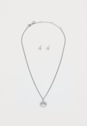 Collana in argento con un pendente circolare adornato da gemme trasparenti, accompagnata da orecchini a perno triangolari in argento abbinati.