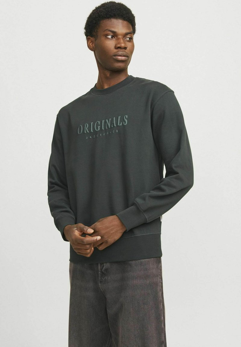 Zwart sweatshirt met "ORIGINALS" in een lichtere tint gedrukt, ronde hals, lange mouwen, ribgebreide manchetten en een losse pasvorm.