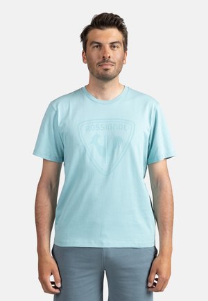 Lichtblauwe T-shirt met een ronde halslijn en korte mouwen, met een subtiele logo in het midden. Zacht katoen materiaal. Minimalistisch ontwerp.