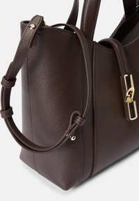 Bolsa tote de couro castanho com um acabamento texturizado, apresentando um fecho dourado polido e um design de alças duplas. Forma compacta e estruturada.