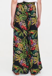 Spodnie o szerokich nogawkach wykonane z lekkiego materiału charakteryzują się kolorowym tropikalnym wzorem w kwiaty, z zielonymi, czerwonymi i różowymi liśćmi na czarnym tle.