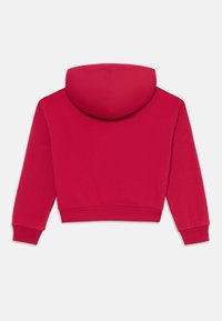 Skraćená mikina v jasne červene farbe, so predným vreckom a nastaviteľnou kapucňou na šnúrku. Mäkka tkanina s prúžkovanými manžetami a lemom.