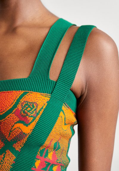 Groene geribbelde tanktop met een levendig oranje en gele abstracte patroon, voorzien van brede banden en een getailleerd ontwerp.