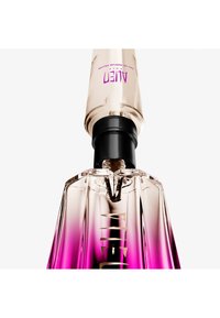 Flacon de parfum transparent avec un dégradé rose et un vaporisateur noir, étiqueté "Alien" en texte violet.