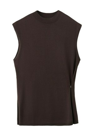 Young woman with light skin and green eyes wearing a sleeveless black top, holding a dark brown suede jacket over her arm.