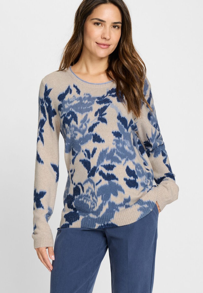 Beiger Pullover mit blauem Blumenmuster, Rundhalsausschnitt, langen Ärmeln, gerippten Bündchen und Saum, weiche Textur. Kombiniert mit blauer Hose.