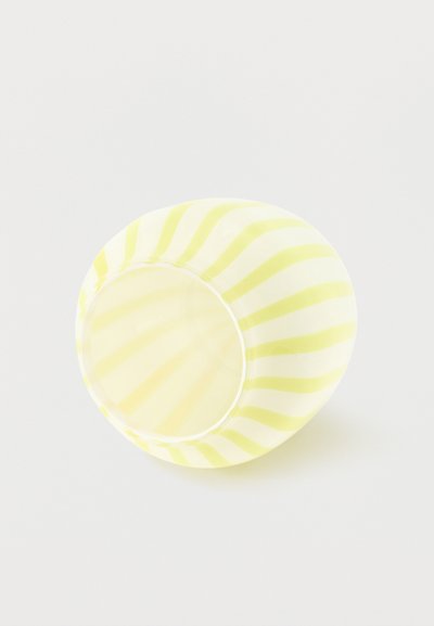 Petit bol rond en tissu avec des rayures diagonales jaunes et blanches sur un fond clair, vu de dessus.